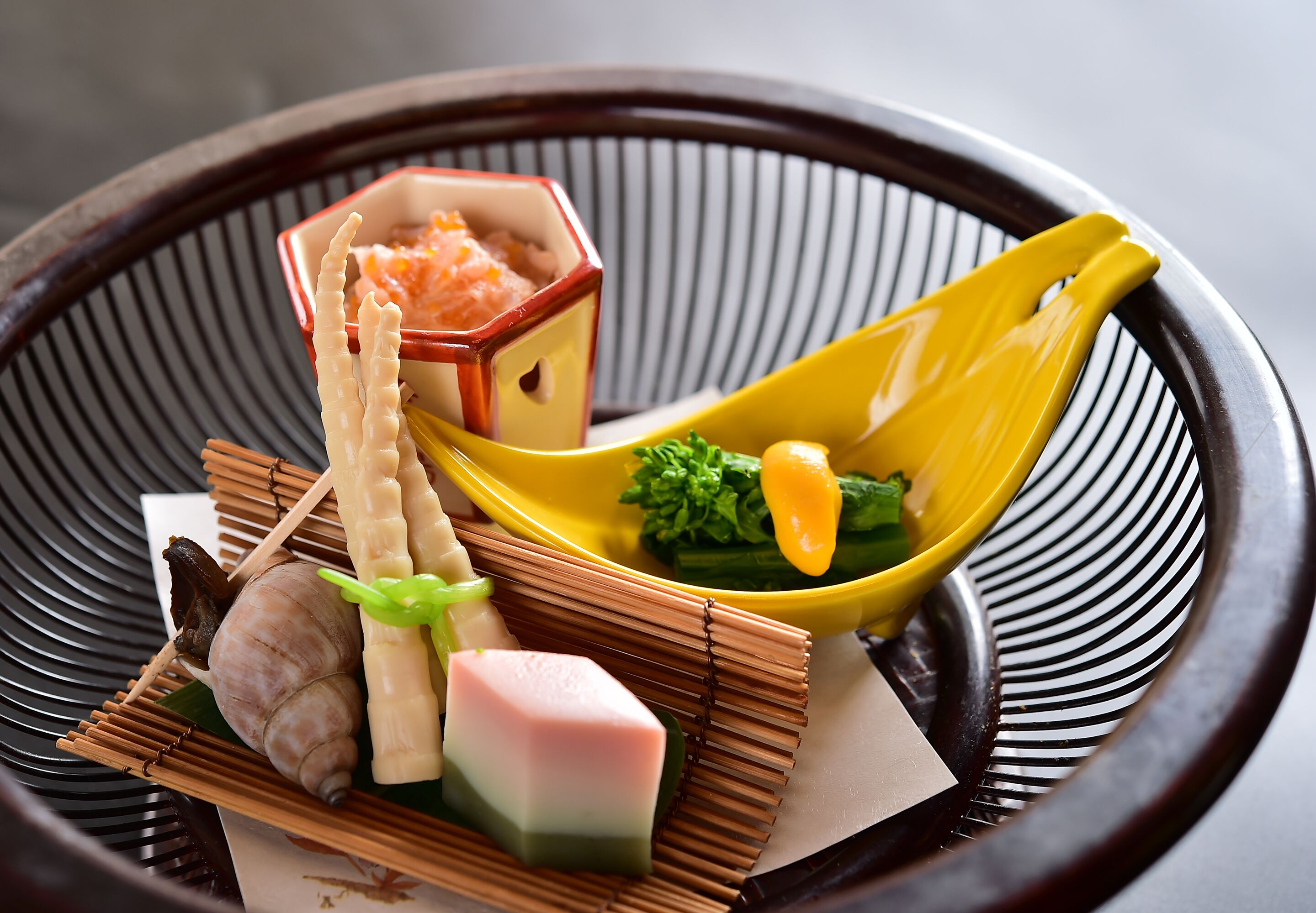 Eine traditionelle japanische Mahlzeit mit verschiedenen Gerichten und Besteck auf einem gewebten Tablett.