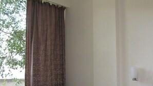 Una habitación con cama, una silla, una mesita y una ventana con cortinas.