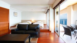 A hotel room with a bed, a sofa, a coffee table, and a balcony with wicker chairs. - Ibusuki Seaside Hotel (Ibusuki)