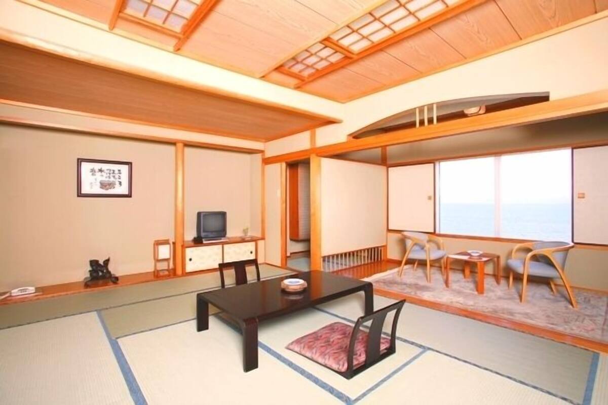 A traditional Japanese-style room with tatami flooring, a low table, and a sofa set.