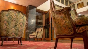 A lobby with ornate chairs and a red carpet.