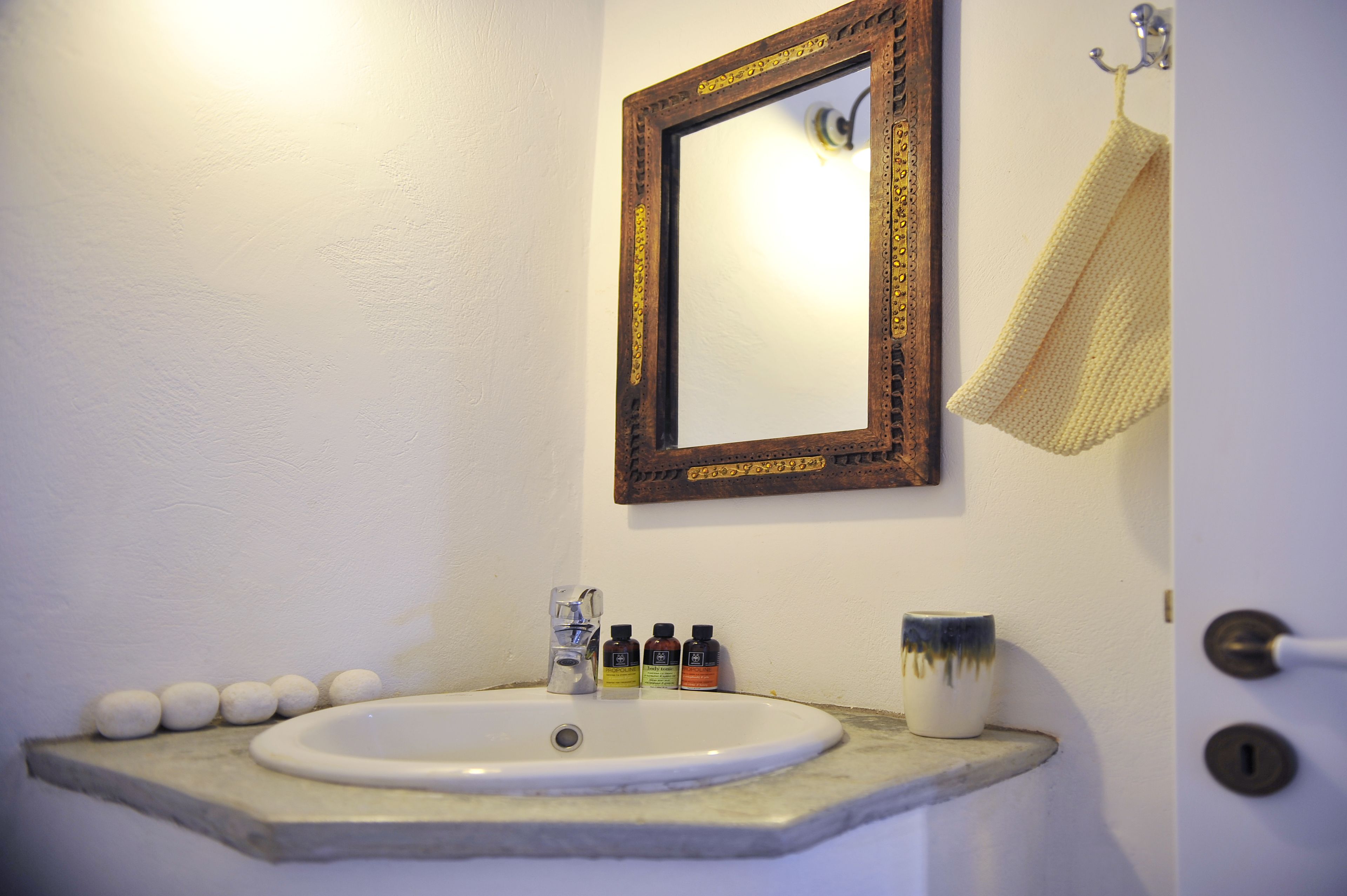 A bathroom with a white sink, a mirror with a decorative frame, and a towel hanging on a hook.