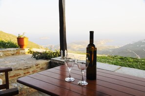 A table with a wine bottle and two glasses, overlooking a scenic landscape.