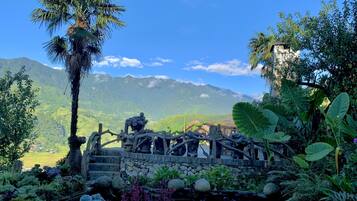 A garden with a stone bridge, a pond, and a mountain backdrop.