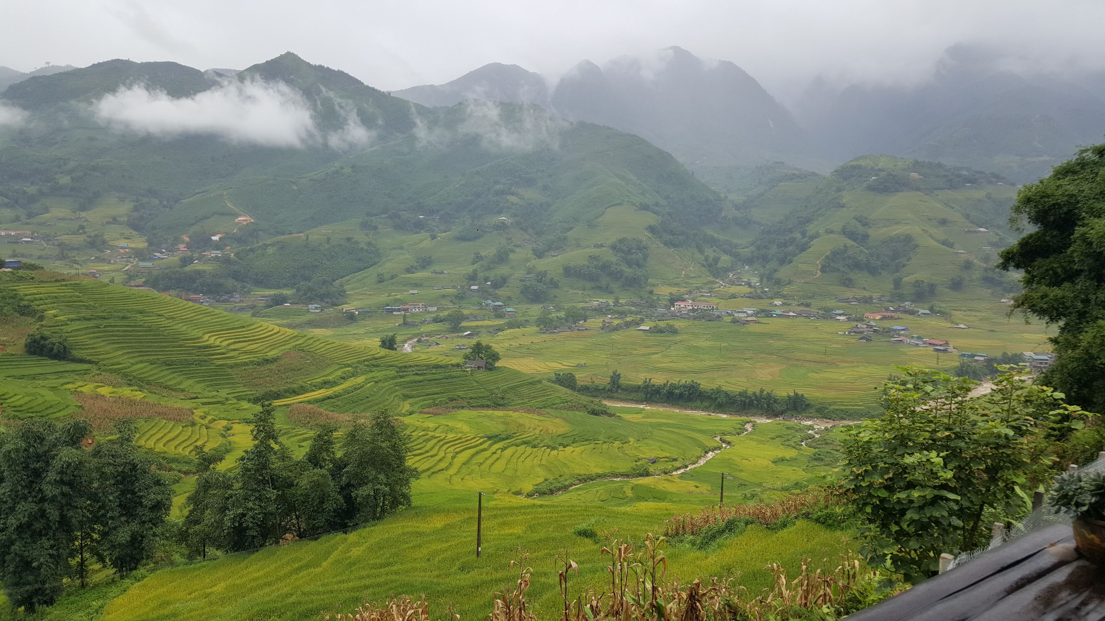 Terraced rice fields, a small village, and mountains in the background.