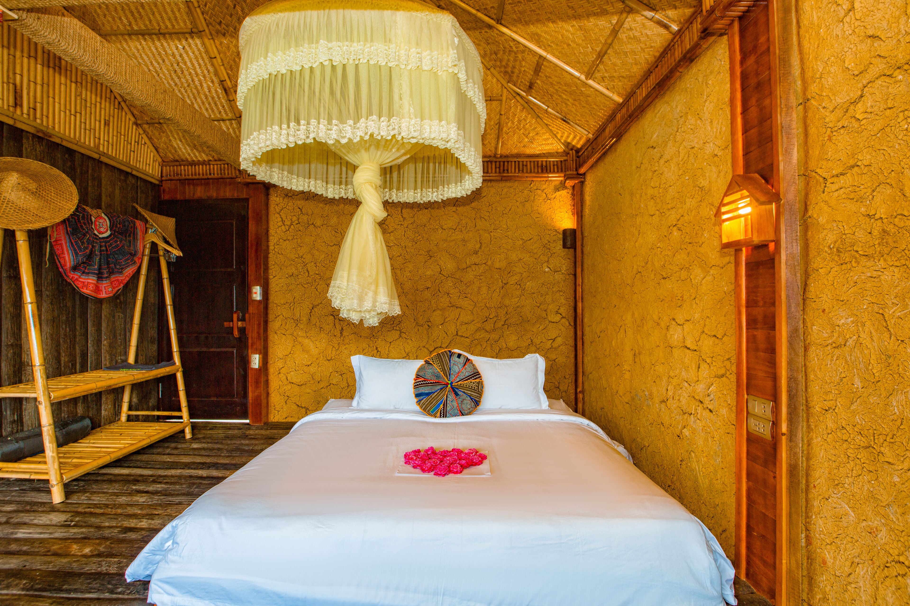 A bed with a white bedspread and a decorative pillow, a hanging light fixture, and a wooden ladder against the wall.