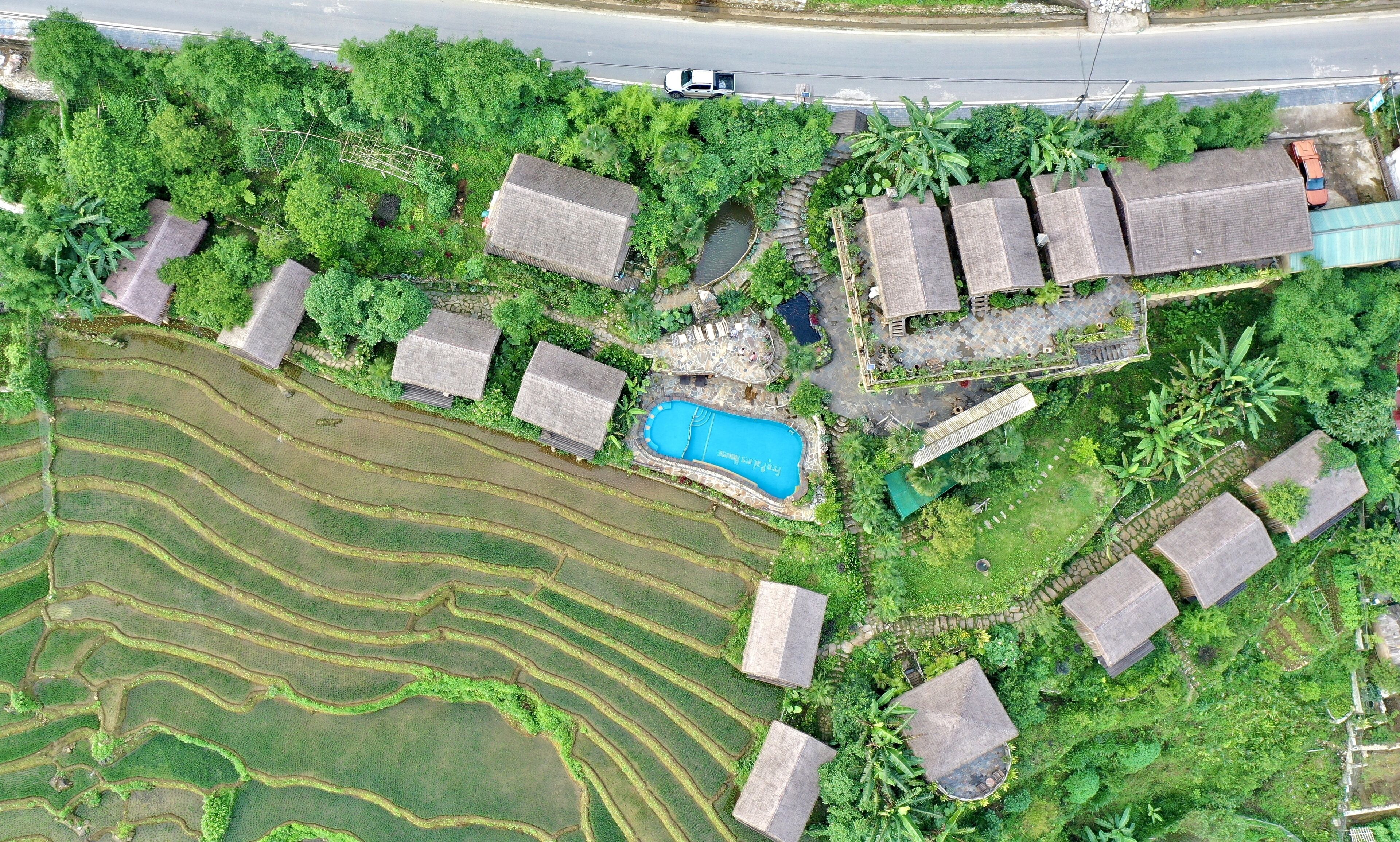 Campi di riso a terrazza, una piscina e diverse case tradizionali con tetti di paglia.