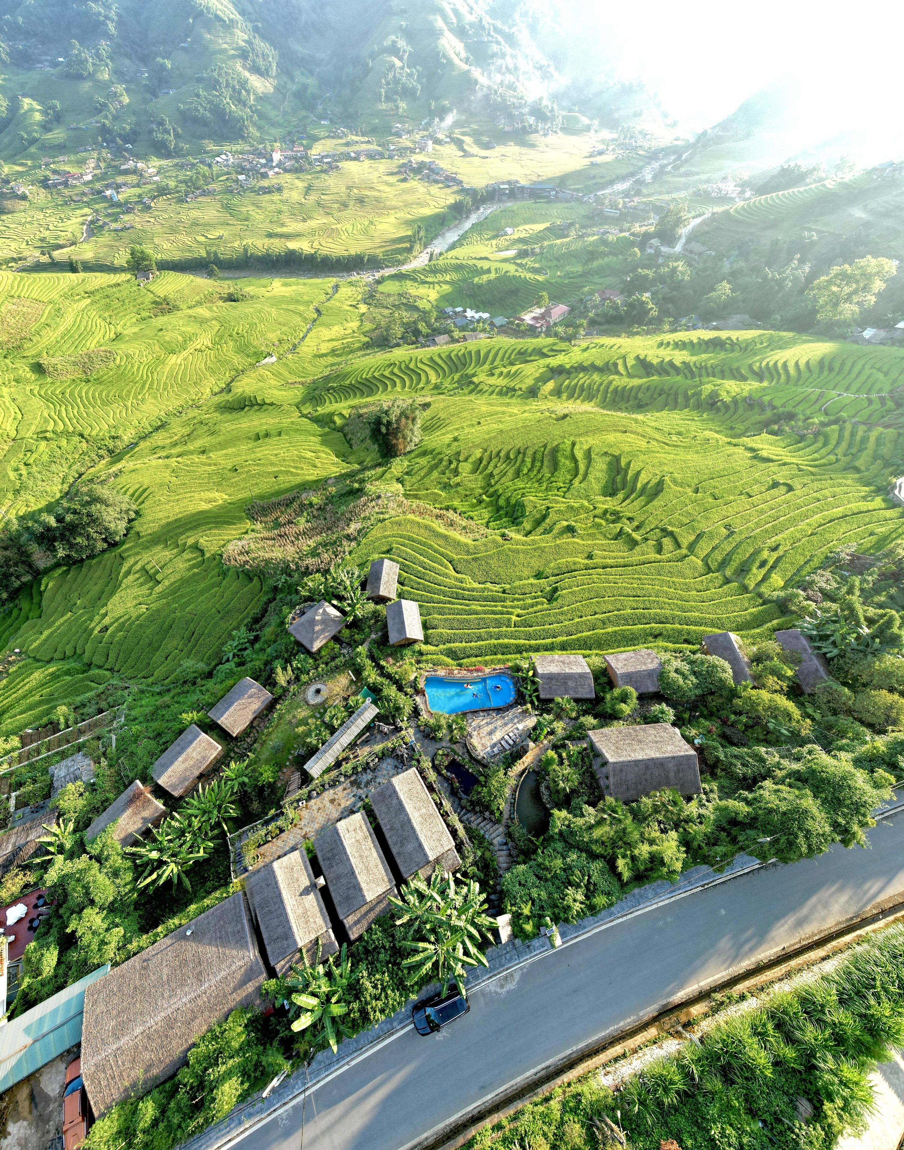 A terraced rice field with a swimming pool and stone buildings.