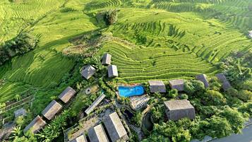 Campo de arroz escalonado con piscina y edificios de piedra.
