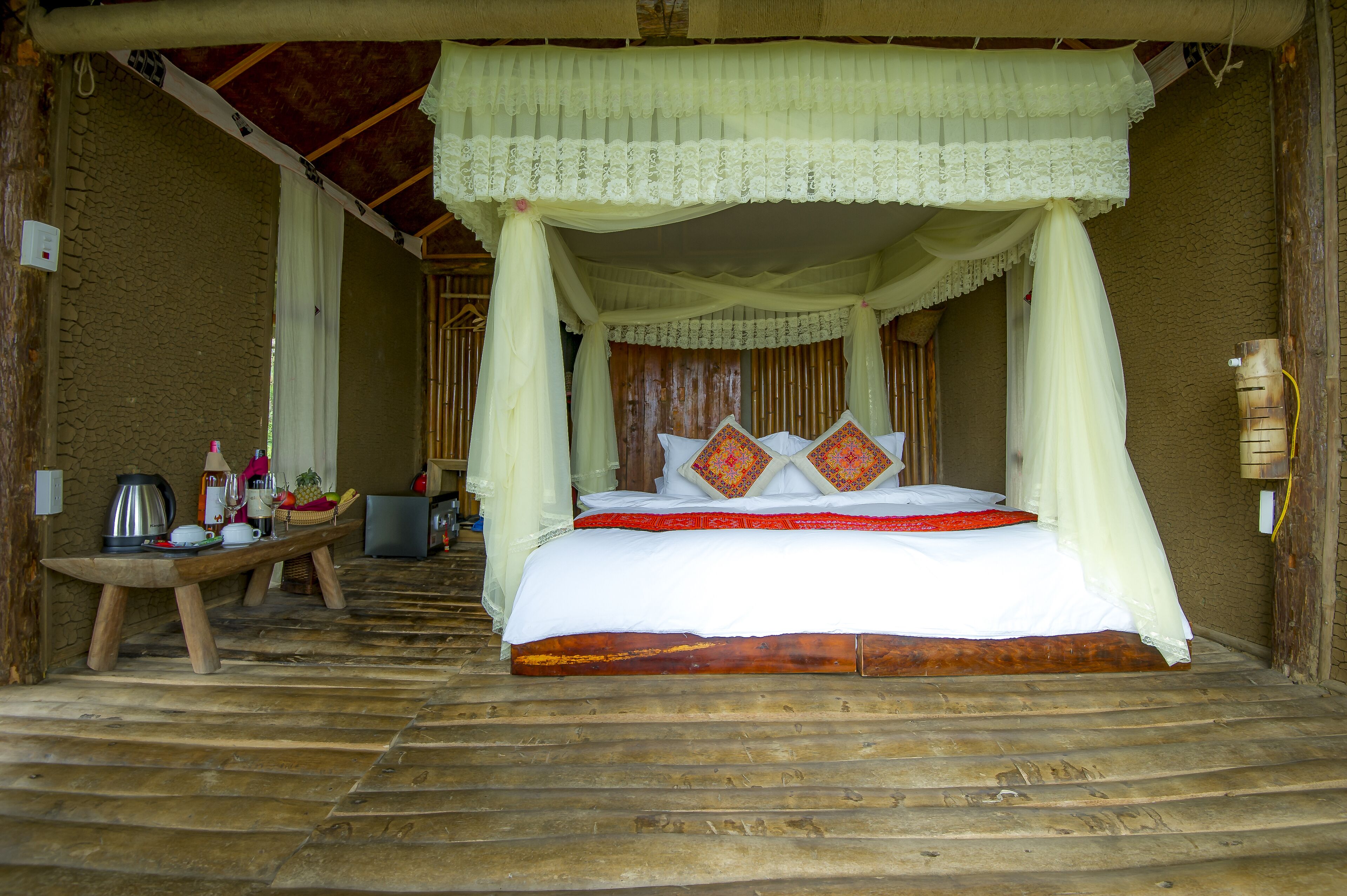 A bed with a canopy, a wooden bench, and a table with various items.