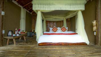 A bed with a canopy, a wooden bench, and a table with various items.