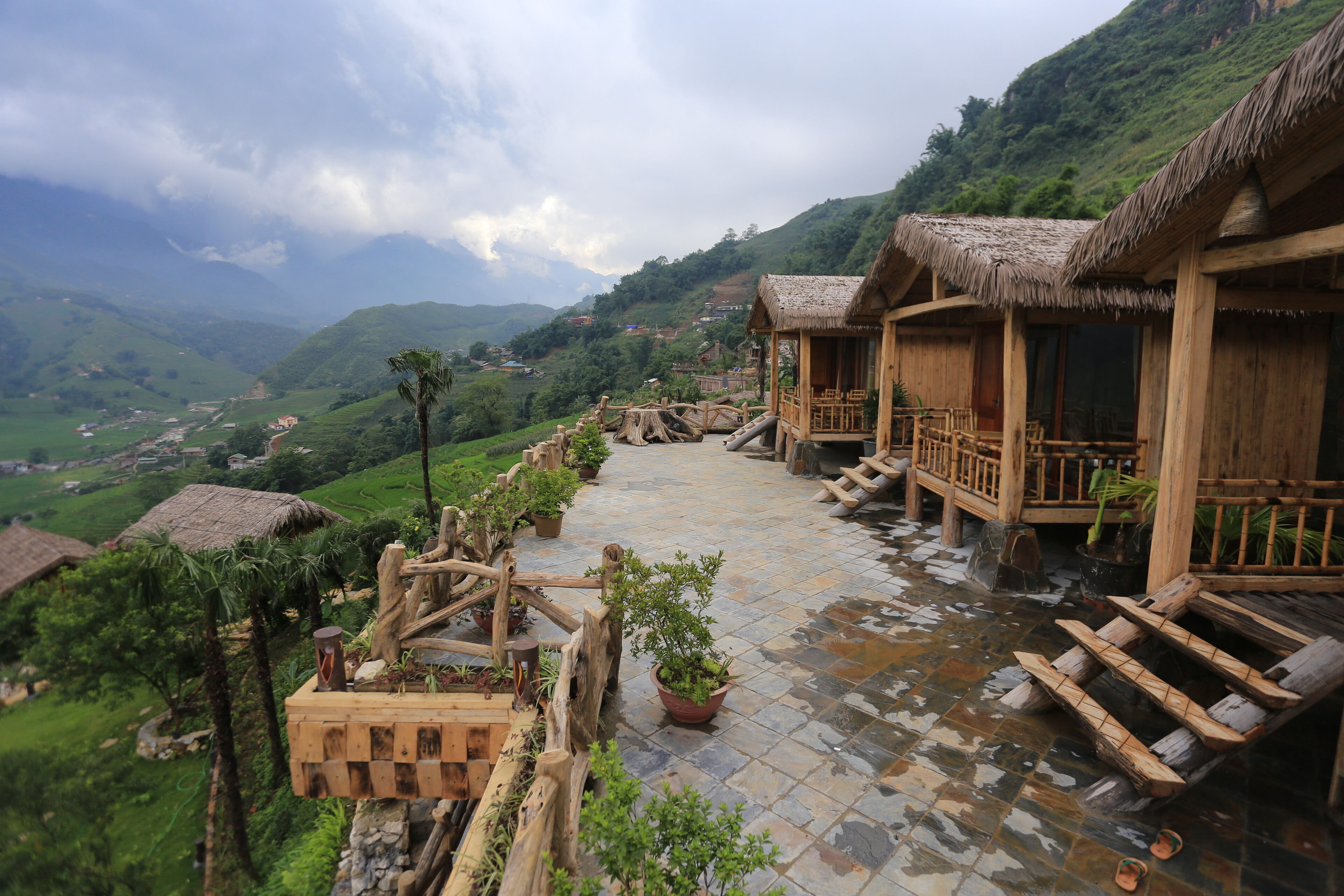 Une construction traditionnelle en bois, avec des toits de chaume, un chemin pavé de pierres et des plantes en pot.