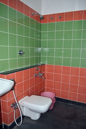 A bathroom with a toilet, sink, and shower. - Metro Park (Chennai)