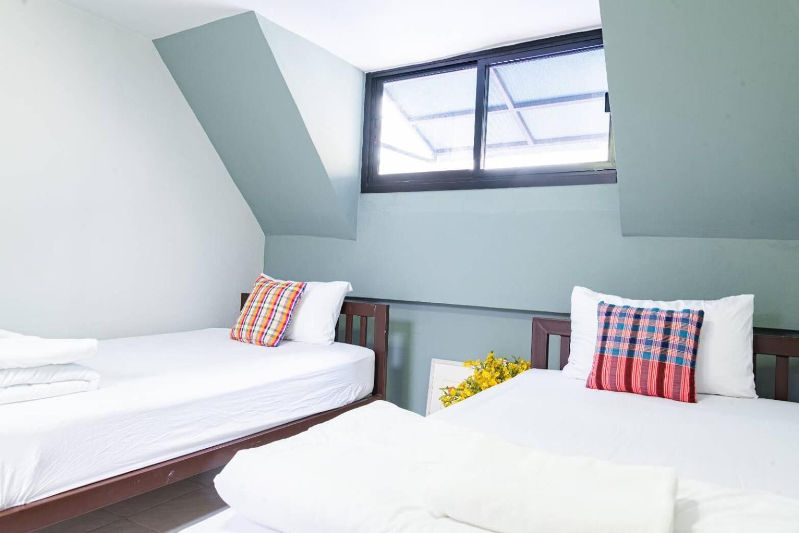 Un dormitorio con dos camas, un tragaluz y una ventana pequeña.