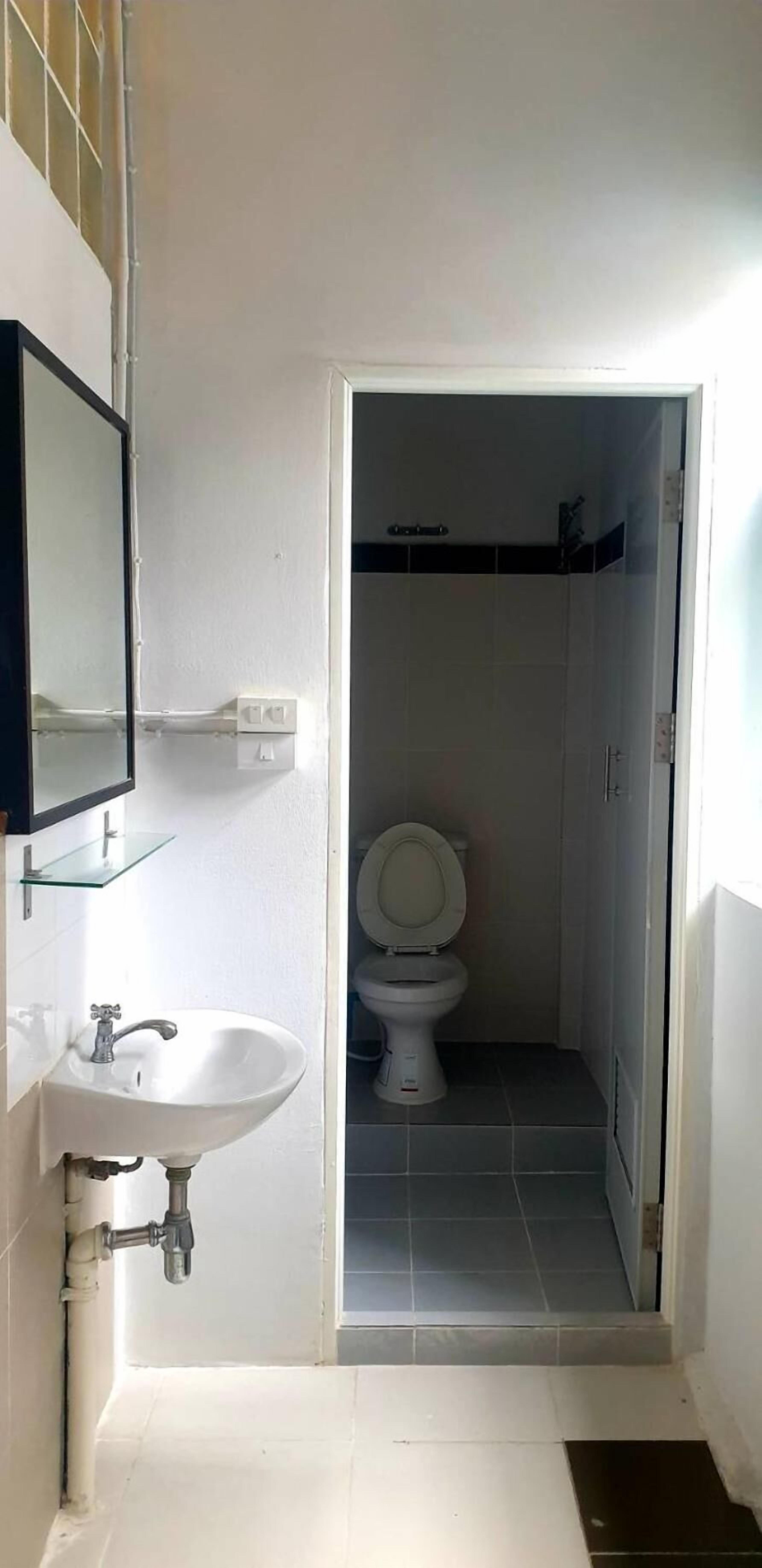 A small bathroom with a white sink, a mirror, and a toilet.