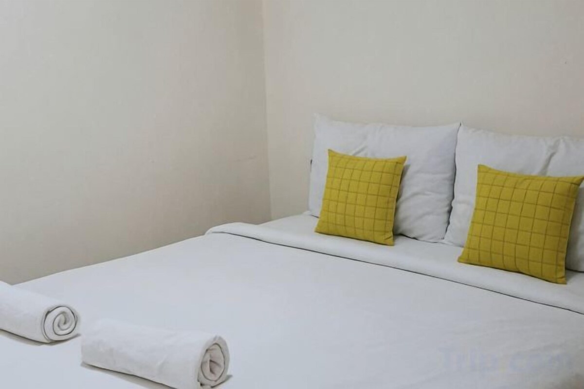 A single bed with white bedding and two yellow pillows.