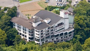 A multi-story building with a flat roof, surrounded by dense greenery. - Hotel Miyama (Chichibu)