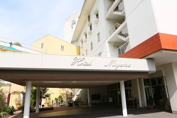 A hotel entrance with a covered walkway, potted plants, and a staircase leading to the entrance.