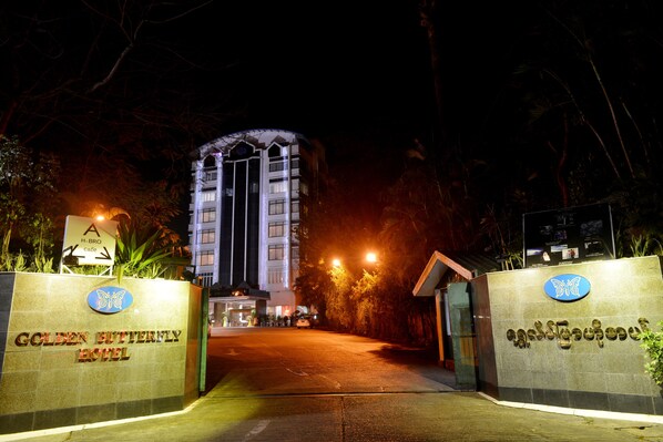 The entrance to the Golden Butterfly Hotel with a signboard, a well-lit pathway, and a building in the background. - Golden Butterfly Hotel (Yangon)