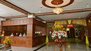 Et hotellobby med en receptionsdisk, en lysekrone og et ur.