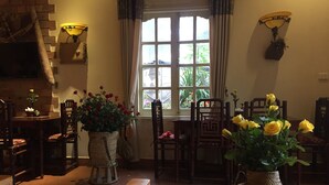 A cozy room with a fireplace, wooden furniture, and potted plants. - Thai Binh Sapa Hotel (Sa Pa)