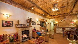 A cozy living room with a fireplace, wicker furniture, and a person sitting by the fire. - Thai Binh Sapa Hotel (Sa Pa)