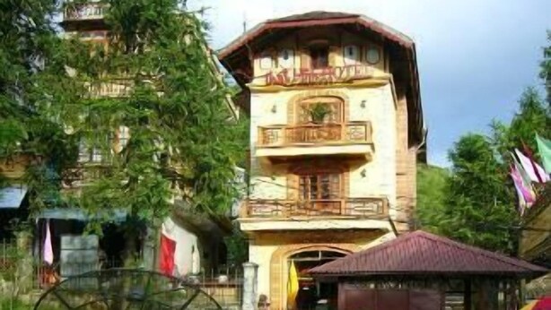 A multi-story building with balconies, surrounded by well-maintained gardens with various plants and flowers. - Thai Binh Sapa Hotel (Sa Pa)