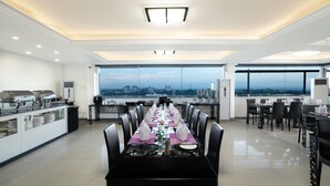 A spacious dining area with a long table set for a meal, large windows offering a city view, and a modern ceiling design. - The Hub Hotel (Yangon)