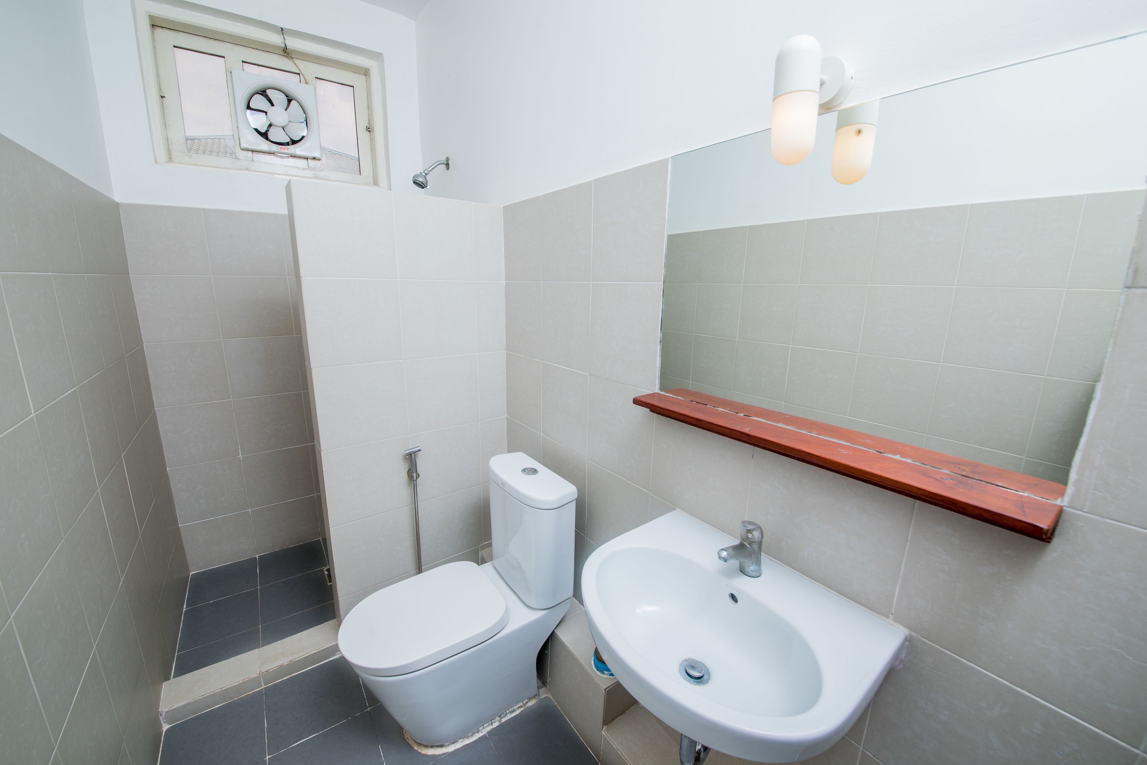 A bathroom with a toilet, sink, and mirror.