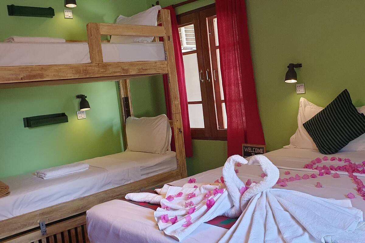 Ein Zimmer mit Etagenbetten, einem Bett mit Rosenblättern und einem 'Welcome'-Schild.