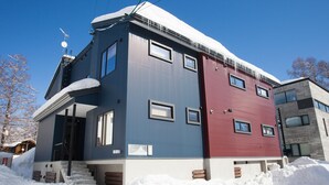 Ein zweistöckiges Haus mit schneebedecktem Dach und einer sichtbaren Satellitenschüssel.