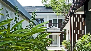 A pathway leading to a building with a covered entrance, surrounded by lush greenery and a well-maintained lawn. - Lombok Senggigi Hotel (Senggigi)