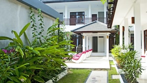 A modern building with a covered outdoor area, a staircase, and a row of white lounge chairs. - Lombok Senggigi Hotel (Senggigi)