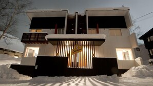 Un edificio moderno a due piani con ingresso coperto di neve e un cartello con scritto "Shirohama".