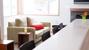 A modern living room with a sofa, a small table with a candle, and a dining table with chairs.