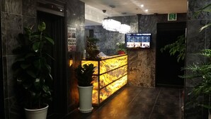 A reception area with a marble wall, a reception desk, and a chandelier. - Hotel BUTI & (Incheon)