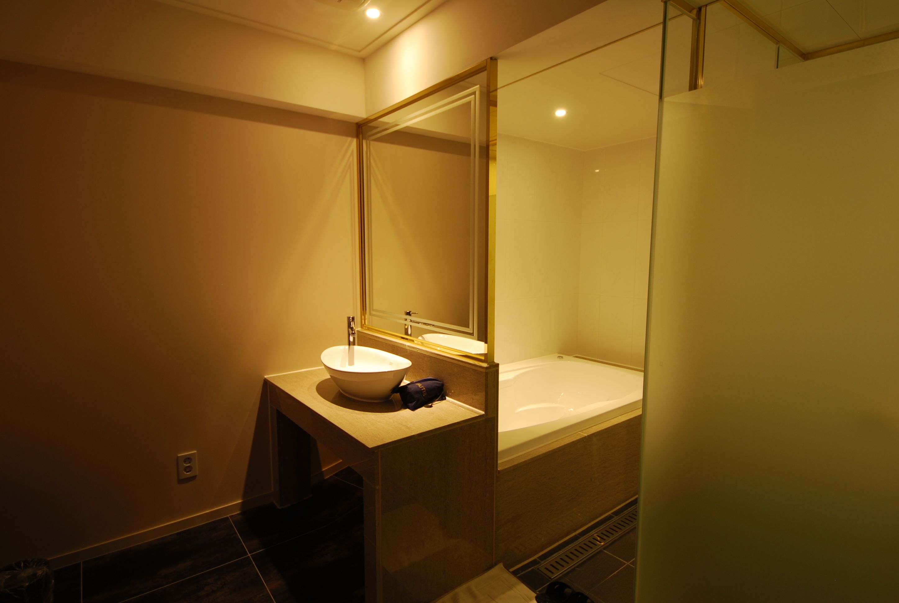 A modern bathroom with a large mirror, a sink, and a bathtub.