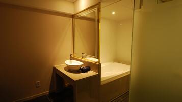 A modern bathroom with a large mirror, a sink, and a bathtub.