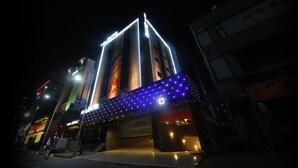 A hotel with a prominent sign, a large illuminated entrance, and a parking sign. - Hotel BUTI & (Incheon)
