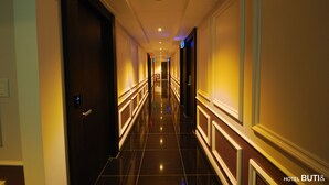A long, narrow hallway with a polished floor, doors on both sides, and a sign indicating the 5F hallway. - Hotel BUTI & (Incheon)
