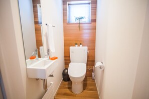 Un baño pequeño con un lavamanos blanco, un inodoro y una ventana con una planta.