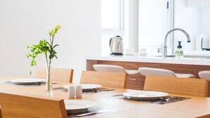 Une table à manger dressée avec des assiettes, des couverts et un vase rempli de fleurs.