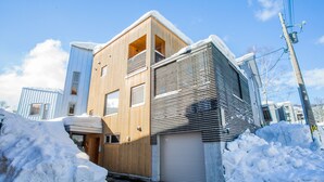Un bâtiment moderne à deux étages, doté d’une façade en bois et d’un garage.