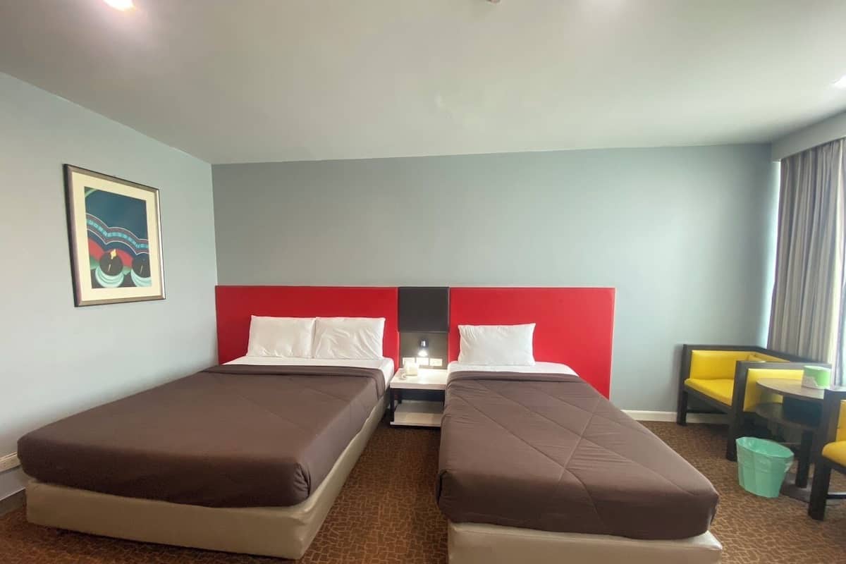 Quarto de hotel com duas camas, uma mesa e uma cadeira.