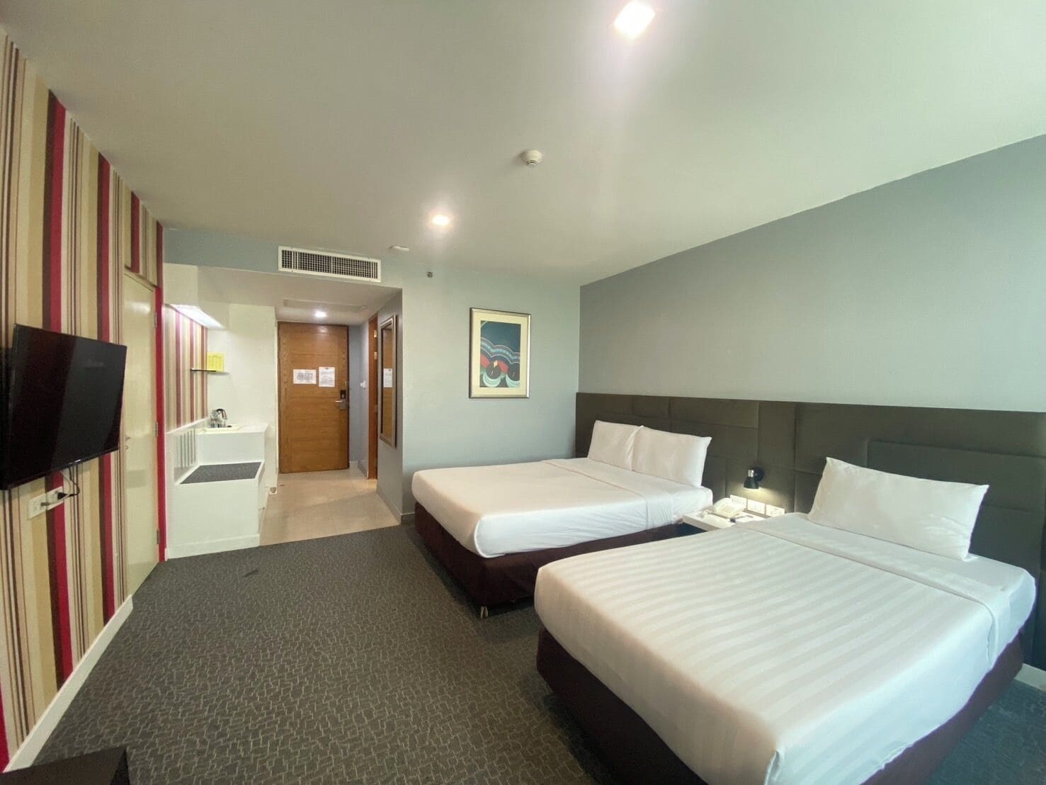 A hotel room with two beds, a TV, a desk, and a bathroom.