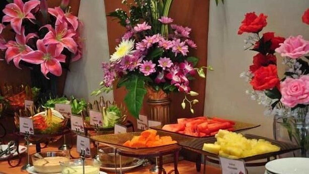 Buffet com diversos alimentos e decoração floral.