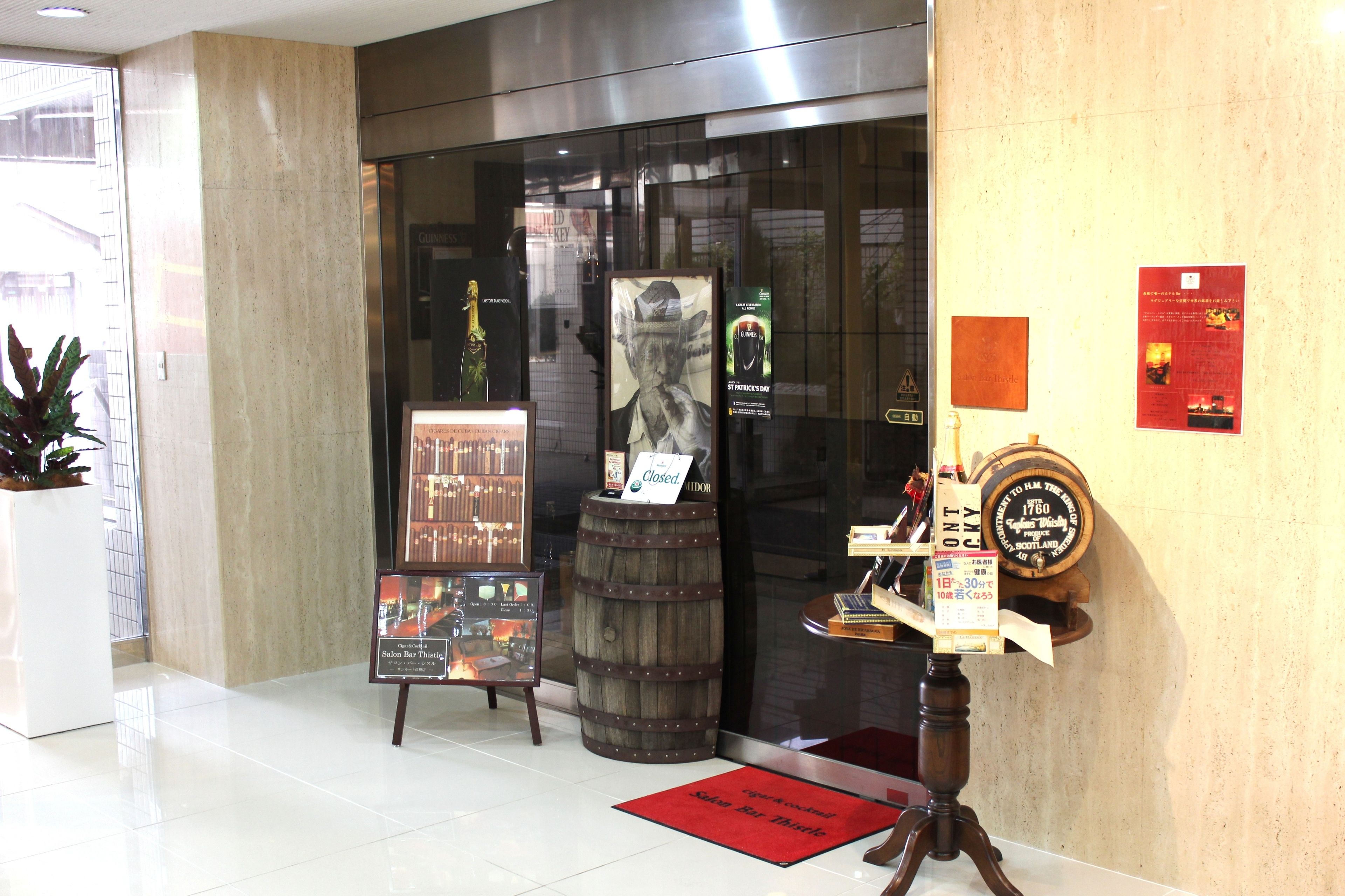A lobby with a wooden barrel, a closed sign, and a red mat.
