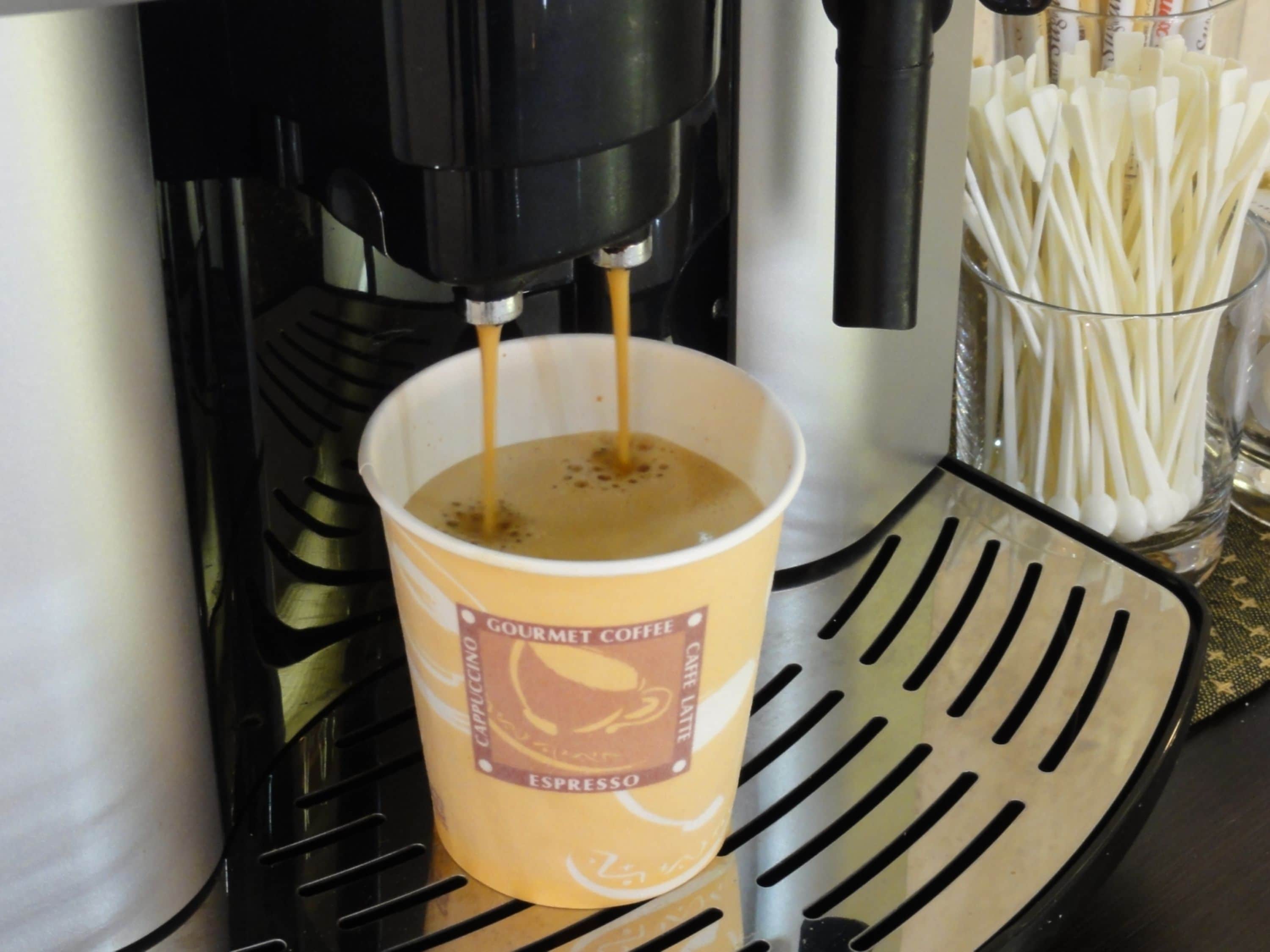 A coffee machine dispensing espresso into a cup labeled 'Gourmet Coffee Espresso'.