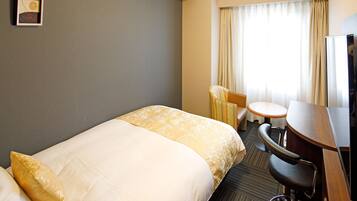 A hotel room with a bed, a desk, a chair, and a television.