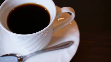 A white cup of coffee with a spoon on a saucer.